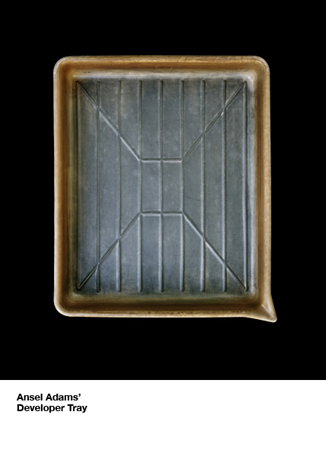 A rectangular developer tray with a ridged base, set against a black background. Text below the object reads “Ansel Adams’ Developer Tray”.