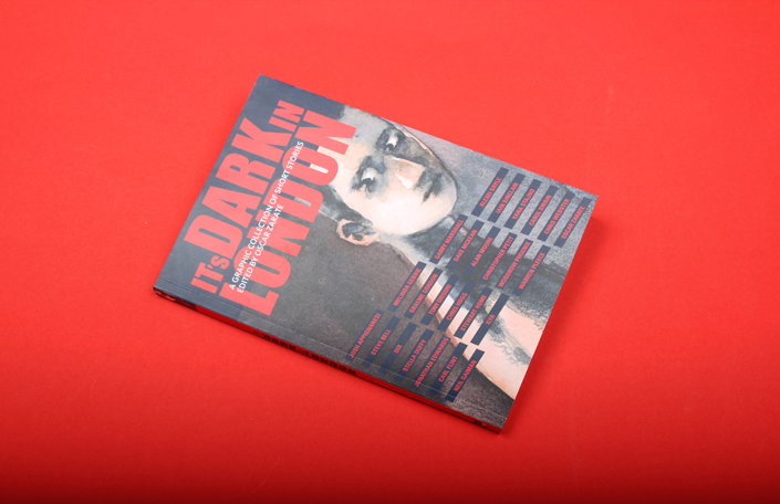 A book titled “It’s Dark in London” lies on a bright red background. The cover features a grayscale portrait of a person’s face, overlaid with red typography and a list of contributors.