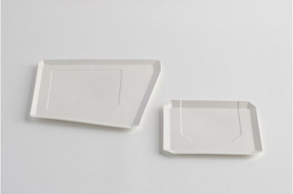 Two white rectangular trays of different sizes are set against a plain white background. Each tray has a raised rim and a subtle, recessed geometric shape on its surface.