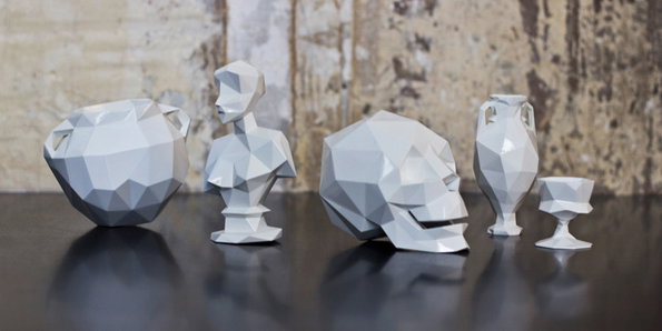 A collection of low-poly white sculptures arranged on a dark, reflective surface. The group includes a bowl, a bust, a skull, a vase and a small chalice.