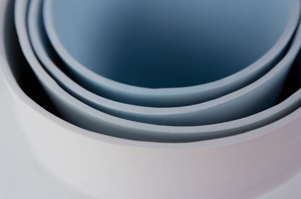 A close-up of concentric circular rings in shades of pale blue and white. The smooth, matte surfaces create a soft, layered tunnel effect.