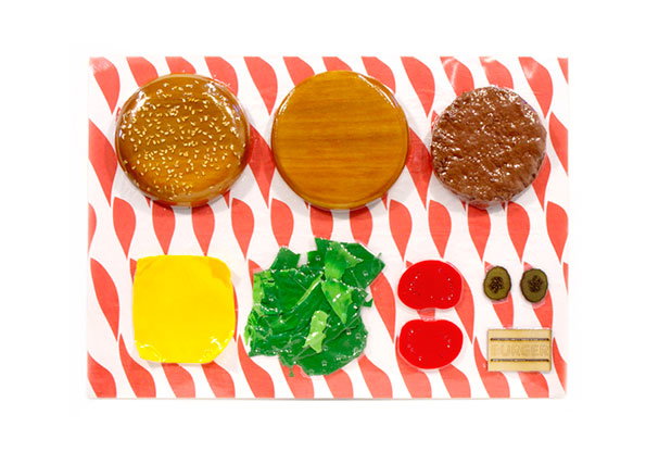 A 3D render of burger ingredients laid out on red and white striped paper. A bun, a slice of cheese, lettuce, tomato and a patty are arranged in a grid.