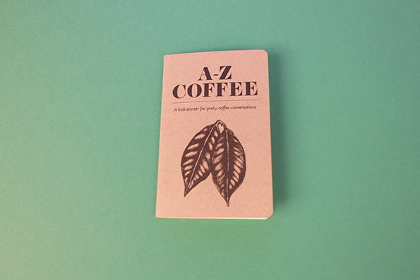 A small, beige booklet centered on a mint green background. The cover features a botanical illustration of coffee leaves and the title “A–Z COFFEE”, with the subtitle “A kick-starter for geeky coffee conversations”.