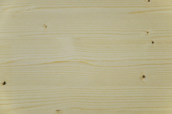 A close-up of a light-coloured wooden surface with a visible grain. A few small, dark knots are scattered across the pale timber.