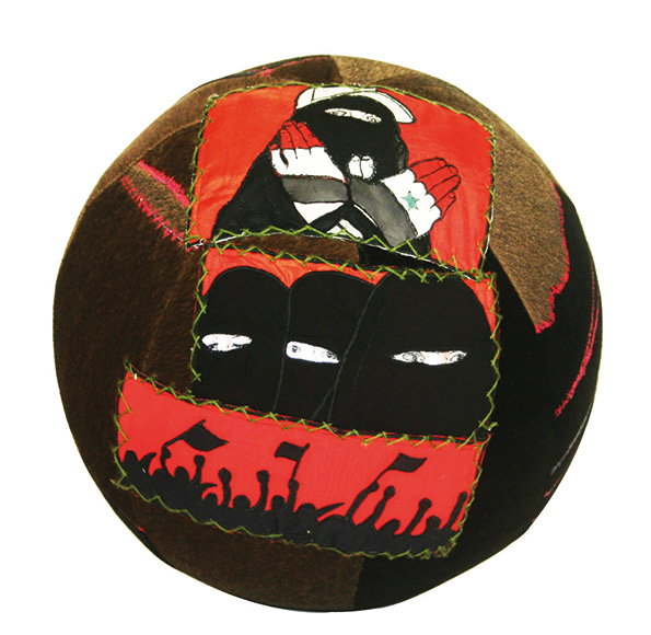 A fabric sphere featuring three stitched-on panels. The panels show figures in black clothing and masks against red backgrounds, with the bottom panel depicting a crowd holding flags.