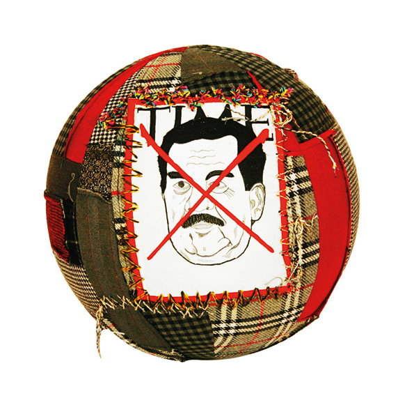 A fabric ball made from patches of red and brown plaid cloth. A stitched-on image of a man with a moustache is crossed out with two red lines.