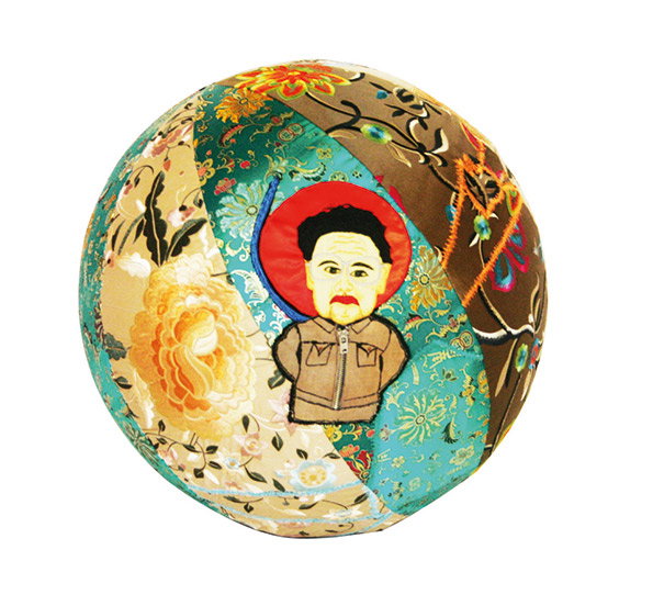 A fabric sphere made from patches of colourful, patterned textiles. At the centre is a small portrait of a person with a red halo, wearing a zipped jacket.