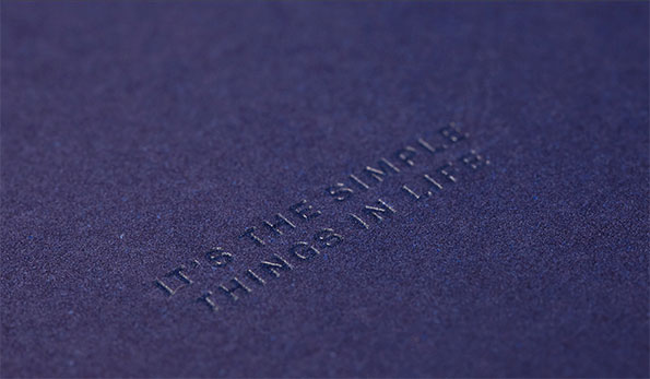 A close-up of a textured purple surface with the words “IT’S THE SIMPLE THINGS IN LIFE” debossed into the material.