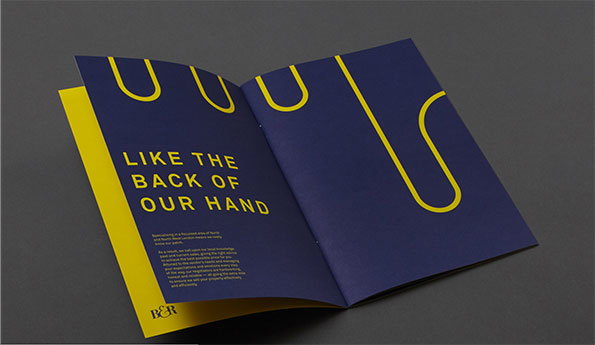 An open brochure with deep blue pages and yellow accents. The left page features the headline “LIKE THE BACK OF OUR HAND” above a block of smaller text and a “B&R” logo.