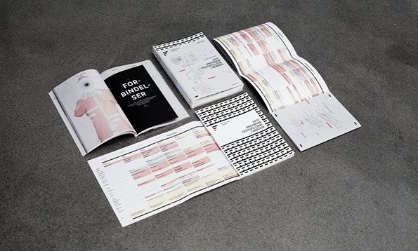 A collection of open booklets and brochures spread across a grey surface. One open page features a figure and the bold text “FOR-BINDEL-SER”.