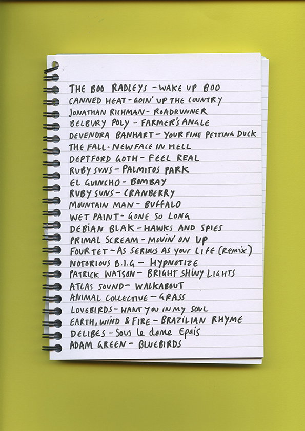 A handwritten list of songs and artists in a spiral notebook, set against a bright yellow background. The list includes entries such as “The Boo Radleys – Wake Up Boo” and “Notorious B.I.G – Hypnotize”.