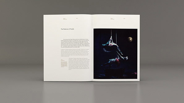 An open book shows a page of text titled “The Patience of Fossils” alongside a dark photograph. The image depicts two figures suspended in a void, one hanging upside down above the other.