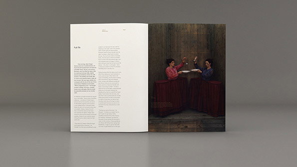 An open book shows a page of text opposite a full-page painting. The artwork depicts two people standing behind red-clothed tables, holding plates and utensils.