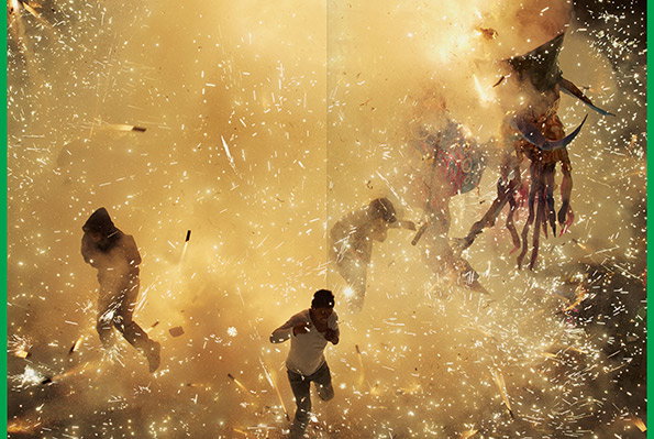 Three people run through a dense cloud of golden sparks and smoke. To the right, a large, horned figure with long tentacles is engulfed in the light.