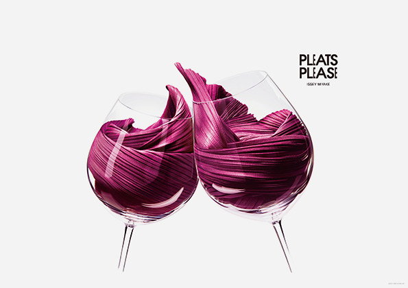 Two wine glasses are filled with swirls of pleated, magenta fabric. To the right, a logo reads “Pleats Please” with “Issey Miyake” written in smaller text below.
