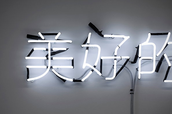 A white neon sign on a grey wall displays Chinese characters. The glowing tubes are held in place by black brackets and visible wiring.