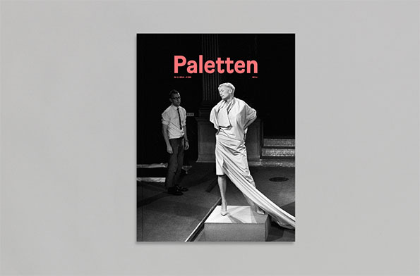 The cover of a magazine titled “Paletten” in bold pink text. A black and white photograph shows a person in a long, draped white garment standing on a plinth, while another person in a white shirt and tie looks on.