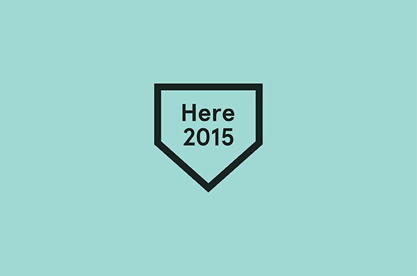 A graphic of a black shield-shaped outline on a pale mint green background. Inside the shield, the text reads “Here 2015”.