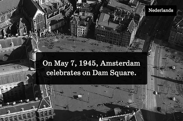 A black and white aerial photograph of a crowded Dam Square in Amsterdam. A black text box in the centre reads “On May 7, 1945, Amsterdam celebrates on Dam Square.”