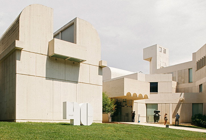The brutalist concrete architecture of the Centre Pompidou-Metz under a pale sky. A large white sculpture of the number “40” sits on a green lawn in the foreground.