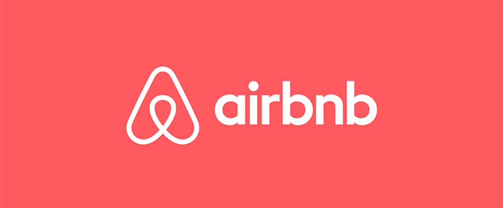 The Airbnb logo and wordmark in white, set against a bright red background.