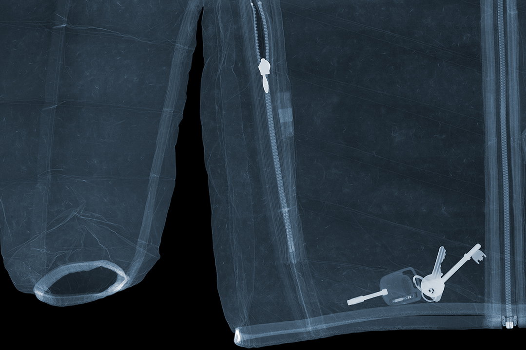 An X-ray of a translucent garment with a visible zip. A set of keys is tucked into a pocket at the bottom.