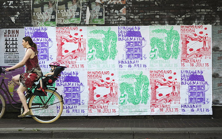 A person rides a bicycle past a wall covered in posters. A child sits in a seat attached to the back of the bike. The posters feature green and red illustrations with the text “Rundgang Design” and “Finkenau 15–16 Juli 15”.