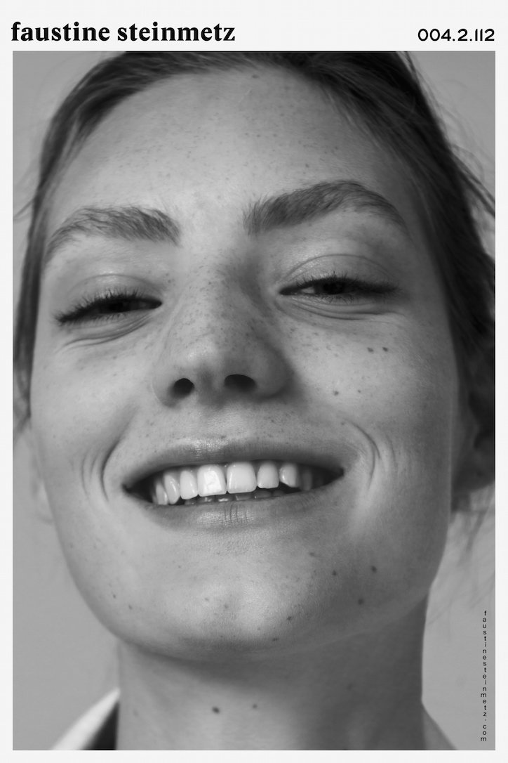 A black and white close-up portrait of a person smiling, showing their teeth. The image is framed by a white border with the text “faustine steinmetz” and “004.2.112” at the top.