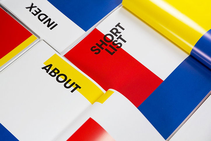 A collection of printed booklets with bold blocks of red, blue and yellow. Legible headings in black sans-serif type read “Index”, “Short List” and “About”.