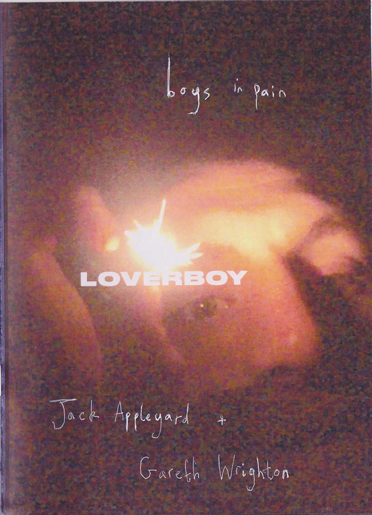 A blurry, high-contrast photograph of a person’s face, partially obscured by a bright flare of light. Handwritten text at the top reads “boys in pain”, while the word “LOVERBOY” is printed in bold white capitals across the centre. The names “Jack Appleyard” and “Gareth Wrighton” are handwritten at the bottom.