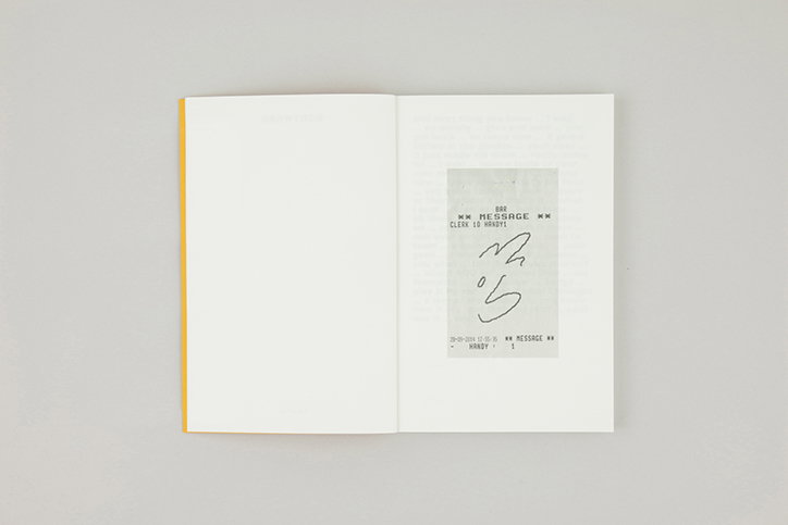 An open book shows a grey rectangular slip of paper pasted onto the right-hand page. The slip contains the word “MESSAGE” and a hand-drawn scribble.