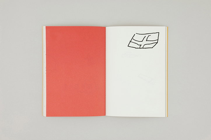 An open notebook lies flat against a grey background. The left page is solid red, while the right page is white with a simple black ink sketch of a rectangular grid.