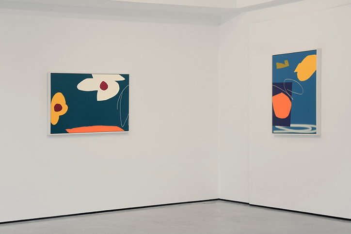 Two abstract paintings hang on the white walls of a bright gallery. The works feature bold, organic shapes in blue, orange, yellow and white.