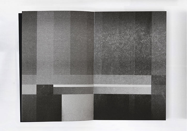 An open book featuring an abstract composition of grey, black and white rectangular blocks. The shapes vary in tone and texture, creating a geometric, architectural feel across the two pages.