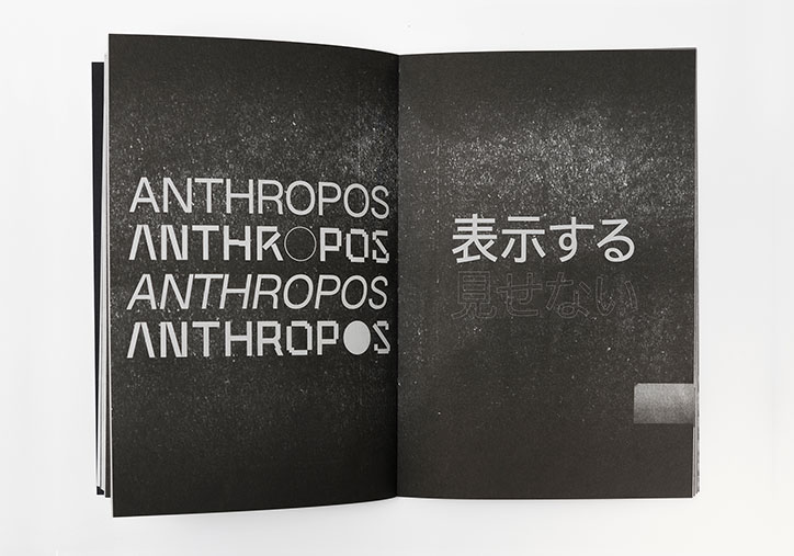 An open book with black pages and white text. The left page repeats the word “ANTHROPOS” four times, with different letters replaced by circles. The right page features Japanese characters.
