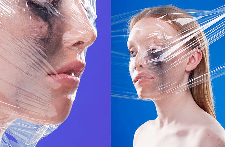 Two portraits of a person with clear plastic wrap tightly wound around their head and face. They wear dark, smudged makeup around their eyes against a bright blue background.