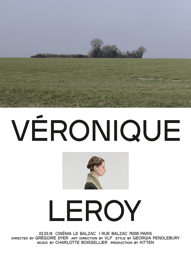 A poster for a film featuring a wide shot of a green field under a grey sky. The text “Véronique Leroy” is split by a small portrait of a person in profile. Smaller text at the bottom reads “03.03.18 Cinéma Le Balzac” and lists the director, art direction, style, music and production credits.