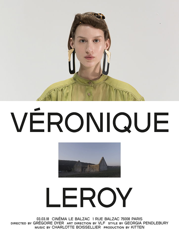 A person wearing a lime green blouse and large, sculptural earrings looks directly at the camera. Below them, a bold typographic layout reads “VÉRONIQUE LEROY” with a small photograph of a stone ruin in the centre. Smaller text at the bottom lists the date “03.03.18”, the venue “Cinéma Le Balzac” in Paris, and the production credits.
