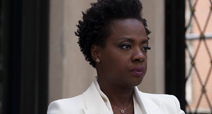 Viola Davis looks off-camera with a serious expression. She wears a white blazer and a delicate gold necklace.