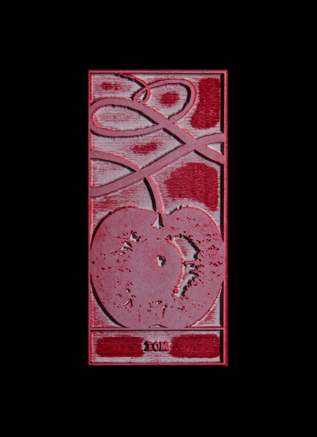 A red embossed illustration of a cherry with a long, looping stem. At the bottom, a small rectangular label reads “TOM”.